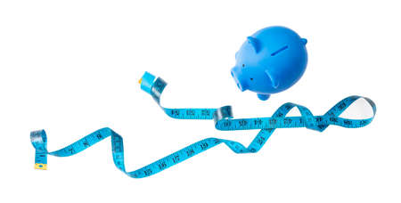 Savings concept. Piggy bank, blue with measure tape and copy space, isolated on white background, banner,の写真素材