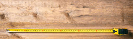 Carpentry tool. Measure tape on wooden background, banner, copy space, top viewの写真素材