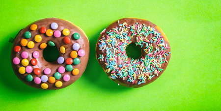 Pastries concept. Donuts with chocolate glaze, sprinkles, 2, top view and isolated on green background.の写真素材