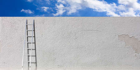 Freedom concept. Metal ladder leaning against a white wall, blue sky background, copy space. 3d...