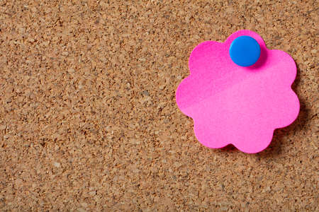 Business concept. Pink sticky note with blue pushpin and blank space, isolated on cork background.の写真素材