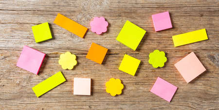 School concept. Sticky colorful notes in various shapes isolated with copy space on wooden...