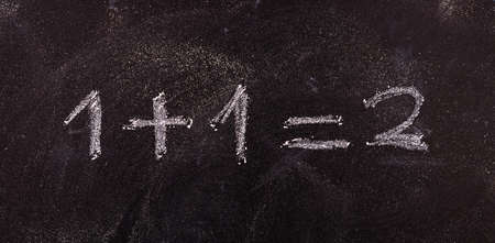 School maths concept. Math simple equation 1+1=2, isolated, on blackboard background.