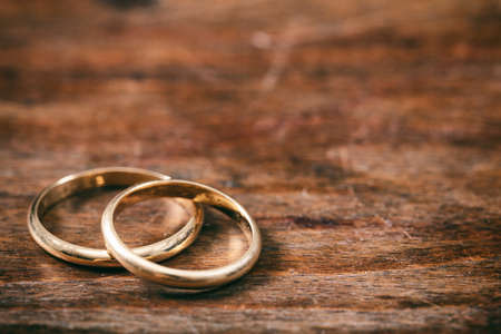 A pair of golden wedding rings on wooden background, copy space