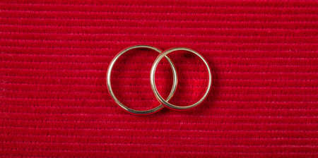 A pair of golden wedding rings on red velvet background, top viewの写真素材