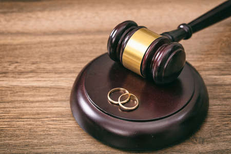 Divorce concept. Wedding rings and judge gavel on wooden background, copy spaceの写真素材