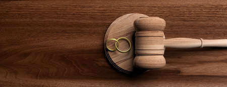 Marriage divorce concept. Wedding rings and judge gavel on wooden background, banner, copy space. 3d illustrationの写真素材