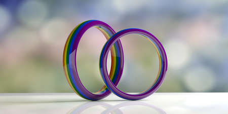 LGBT relationship. Pair of gay pride colors wedding rings isolated on white table, blur pastel...