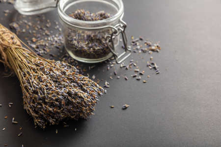 Herbs concept. Dried lavender bouquet on black tabletop background and in glass jar, copy space.の写真素材