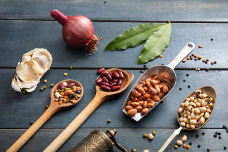 Healthy diet concept. Top view of flat lay of assortment of legumes on black wooden tabletop background, in scoop and ladles and grater.の写真素材