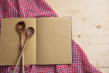 Cooking recipe.Blank notebook, kitchen utensils and red tablecloth on wooden table, top view, copy spaceの写真素材