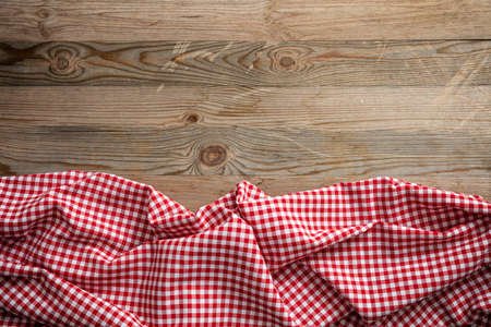 Red and white checkered picnic tablecloth on wooden background, copy spaceの写真素材