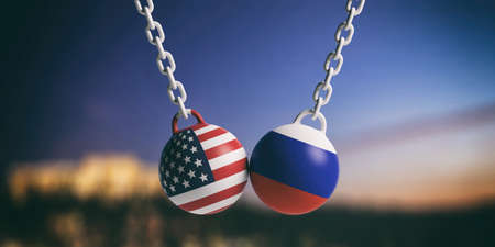 US of America and Russia relations. USA and Russian flags wrecking balls swinging on blue cloudy sky background. 3d illustrationの写真素材