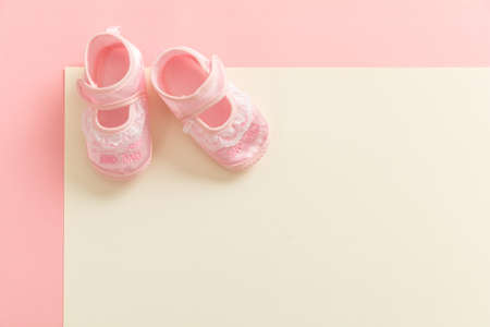 Baby girl shoes, shower invitation concept on pastel colors background, copy space, top view