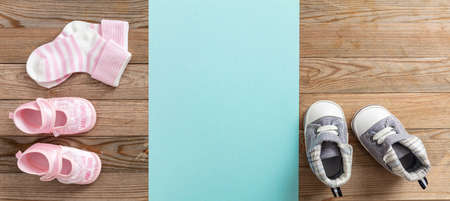 Baby boy and girl shoes and socks on wooden background, banner, copy space, top view