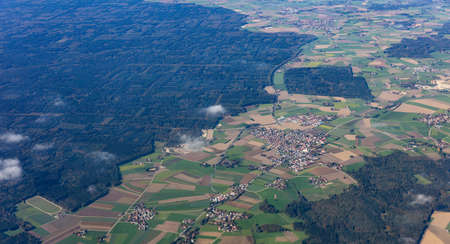 Agricultural fields and houses from above. Aerial view out of a plane window.