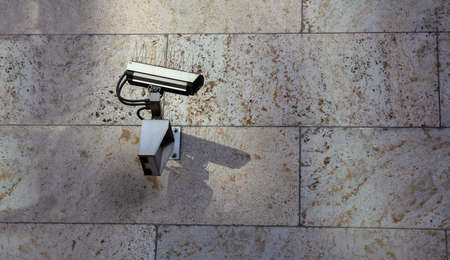 Security concept. Surveillance CCTV Camera on stone wall building facade, copy spaceの写真素材