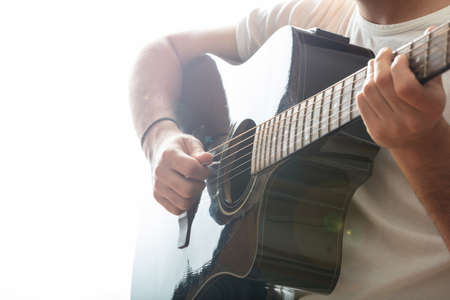 Young man playing guitar, close up view, white background