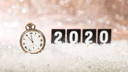 2020 New Years eve celebration. Minutes to midnight on an old watch, bokeh festive backgroundの写真素材
