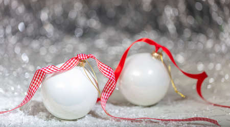 Christmas white balls, red ribbon and snow, abstract bokeh lights backgroundの写真素材