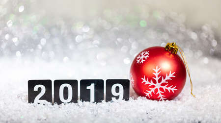 Christmas red ball and new year 2019, on snow, abstract bokeh lights background, copy spaceの写真素材