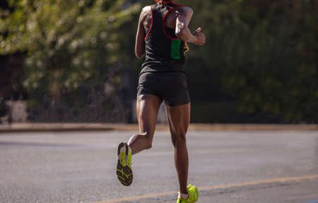 Running in the city roads. Young woman runner, back view, blur background, copy space