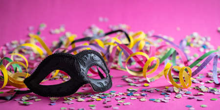 Carnival party. Black mask, streamers and confetti on bright pink background, bannerの写真素材