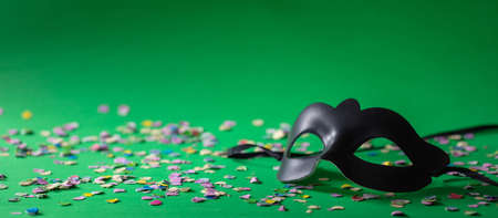 Carnival party. Venetian mask and confetti on green background, banner, copy space