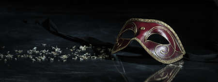 Carnival time. Venetian mask red and gold color on black background, reflections, bannerの写真素材