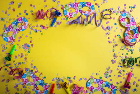 Carnival or birthday party. Confetti and serpentines on bright yellow background, top view, copy spaceの写真素材