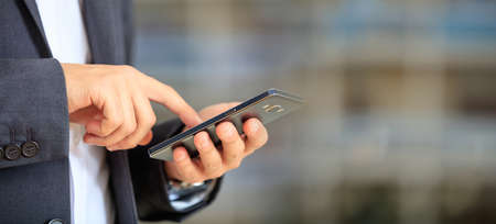 Man holding phone. Young businessman in business wear using a mobile, closeup view on smartphone, banner, copy spaceの写真素材