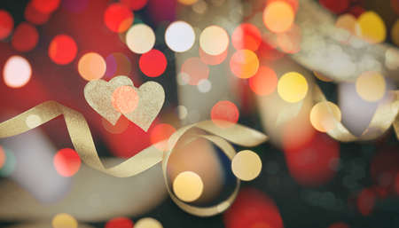 Valentines day.  Top view of red and golden hearts with satin ribbon against black background,...