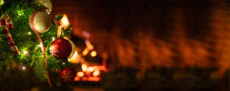 Christmas time, warm home. Christmas tree close up on blurred burning fireplace background, banner, copy spaceの写真素材