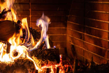 Christmas time, cozy fireplace. Wood logs burning against red firebricks background, relaxation and warm home, copy space,の写真素材