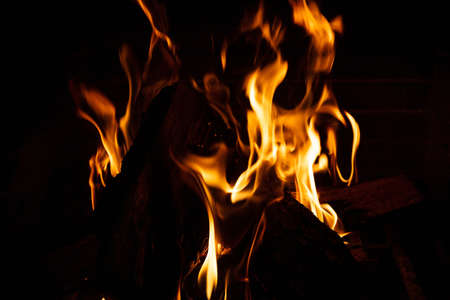 Cozy fireplace. Wood logs burning, dark background, relaxation and warm home, closeup view with detailsの写真素材