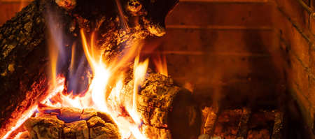 Cozy fireplace. Wood logs burning, dark background, relaxation and warm home, banner, banner, copy space, closup viewの写真素材