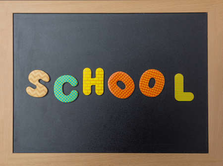 School concept. Black chalkboard with wooden frame, word, text school in colorful letters