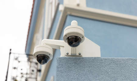 Surveillance CCTV Security Camera system on a blue painted building facade, closeup view