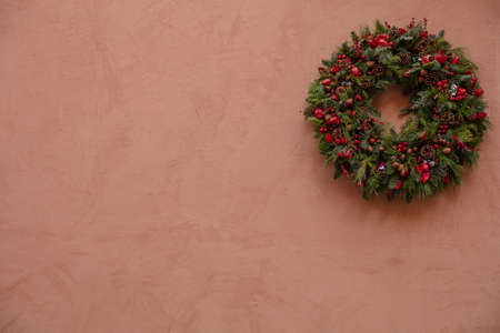 Christmas wall decoration. Christmas wreath on a stucco painted wall, residential building facade, copy spaceの写真素材