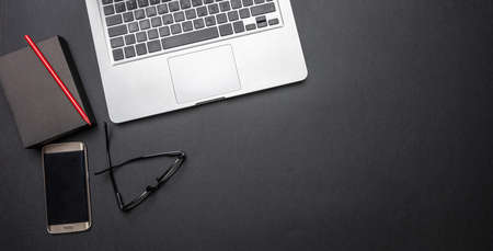 Modern workspace. Computer laptop and mobile phone on black office desk, top view, copy space