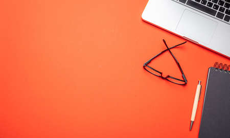 Modern workspace. Computer laptop and notepad on orange color office desk, top view, copy spaceの写真素材