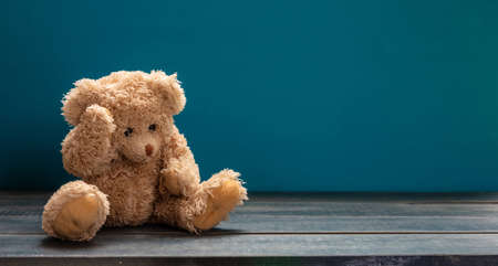 Blue Monday, depression concept. Teddy bear sad, holding his head, sitting on the wooden floor, blue empty room background, copy spaceの写真素材