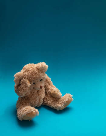 Blue Monday, depression concept. Teddy bear sad, holding his head, sitting in blue empty room...