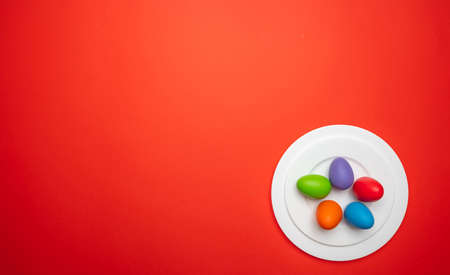 Easter eggs, pastel colors painted in a white plate, orange color background, copy space, top view