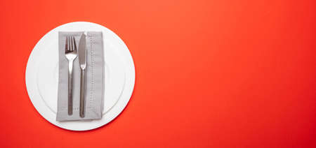 Table place setting on red. Set of empty white plates and cutlery on red, orange color background, banner, top view, copy spaceの写真素材