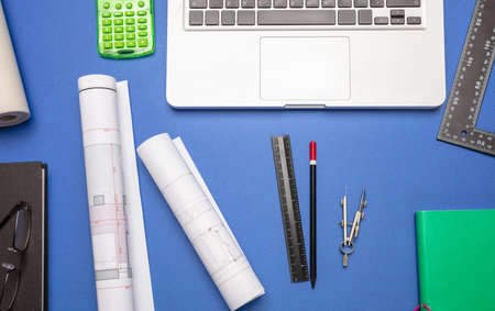 Architect engineer construction site office desk. Project blueprints, stationery and computer laptop...