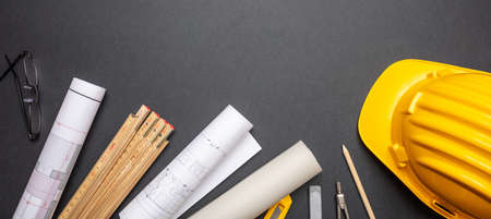 Architect engineer workplace, construction site desk. Project blueprints, yellow hard hat and...
