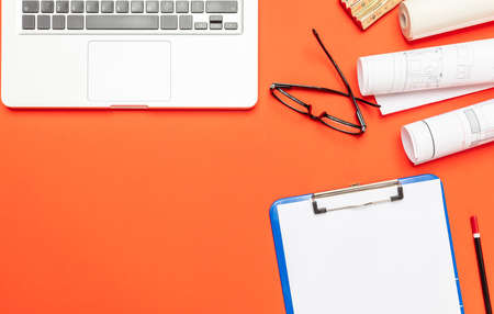 Architect engineer construction site office desk. Project blueprints, stationery and computer laptop on orange color, copy space, top viewの写真素材