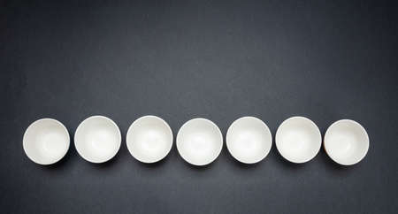 White clean ceramic bowls in a row, black color background, copy space, top viewの写真素材