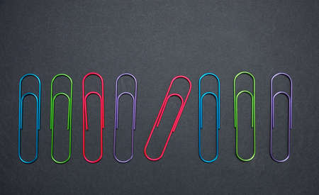 Business, school supplies. Colorful big paper clips on black color backgroundの写真素材